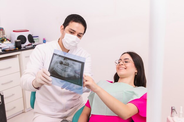 Foto dentista che spiega al suo paziente la procedura di trattamento con una radiografia dentale nell'ufficio dentistico