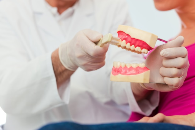 Dentista che spiega a spazzolatura di denti al paziente