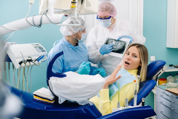 The dentist explains the details of the Xray to his colleague the patient is surprised by what is happening