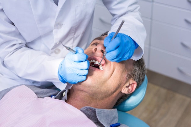 診療所で男性に歯科治療をしている歯科医