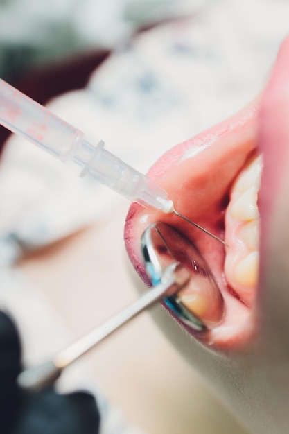 Photo dentist giving injection for anesthetizing his patient