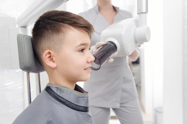 歯科医の手が歯科医院の小さな男の子のために顎のX線画像を作成します