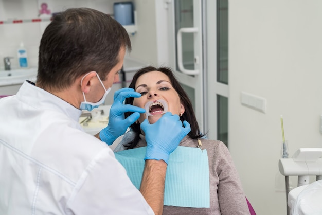 Mani del dentista con strumenti e primo piano del viso del paziente