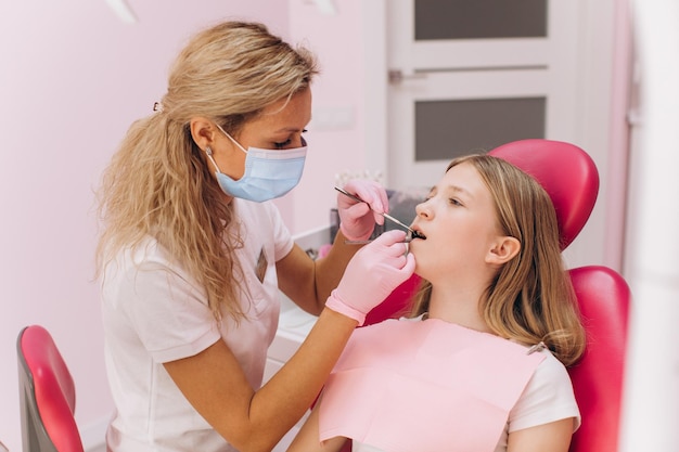 A dentist and her assistant examine the teeth of a teenage girl