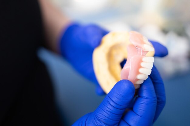 Foto dentista che tiene una protesi dentale artificiale della mascella inferiore piatto del dente della porcellana dello zirconio