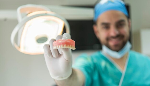 Photo dentist holding ceramic dental bridge