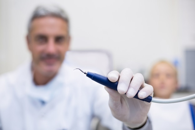 Photo dentist holding dental tool