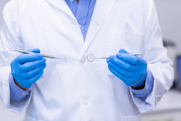 Dentist holding dental tools at dental clinic