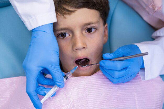 少年を診察しながら医療機器を保持している歯科医