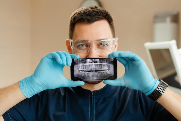 dentist holding a phone showing a panoramic x ray of the jaw