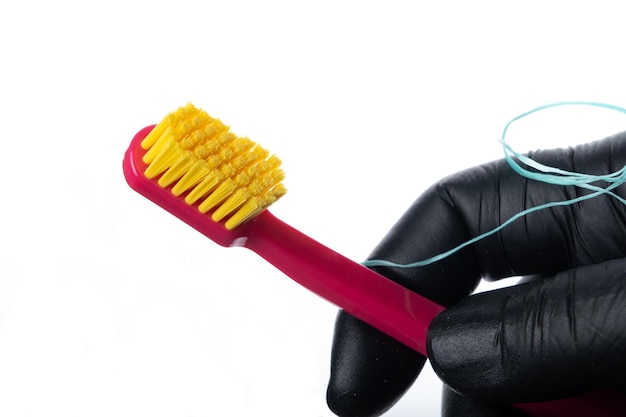 Foto dentista che tiene spazzolino e filo interdentale messa a fuoco selettiva