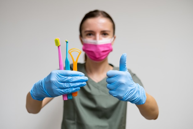 Dentist holding toothbrushes and shows thumb up