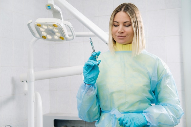 The dentist holds an injection syringe for the patient in the office