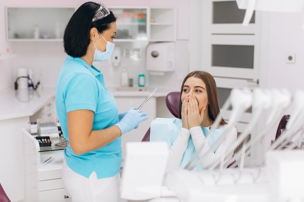 The dentist injects anesthesia to the girl patient she is scared