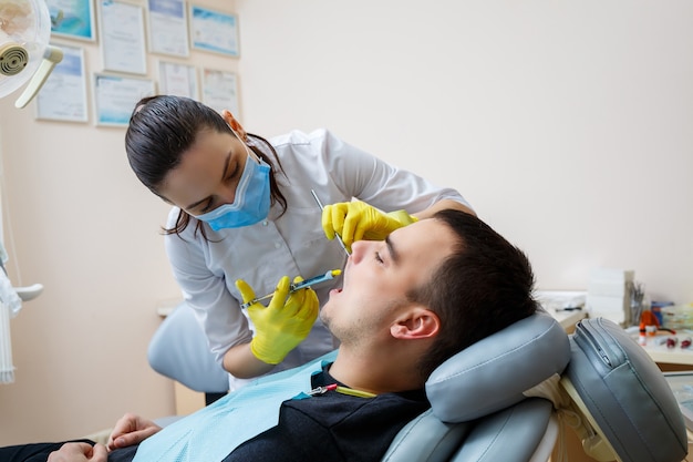 Il dentista inietta il paziente nella gengiva per anestetizzare i denti. trattamento del cavo orale. cure odontoiatriche. foto di alta qualità