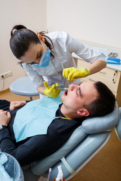 Foto il dentista inietta il paziente nella gengiva per anestetizzare i denti. trattamento del cavo orale. cure odontoiatriche. foto di alta qualità