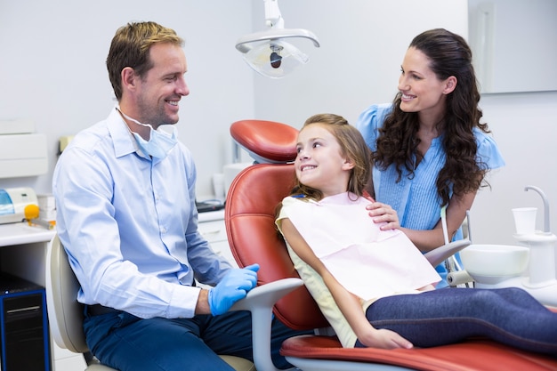 Dentist interacting with mother and daughter while dental examination