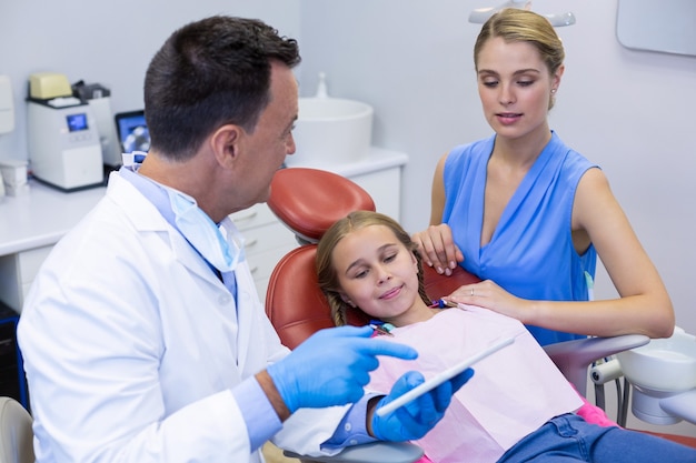 Dentist interacting with young patient and her mother