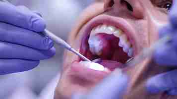 Photo a dentist is examining a patients teeth with a mouth mirror and a dental explorer the patient is sitting in a dental chair with his mouth wide open