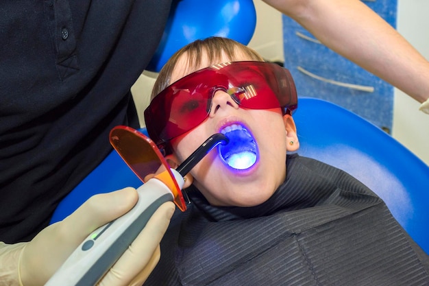 Foto il dentista sta esaminando i denti dei pazienti con l'apparecchiatura a luce uv
