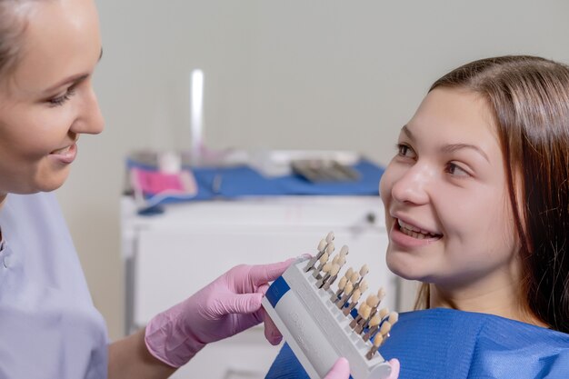 The dentist is trying to choose the right color for the teeth implants