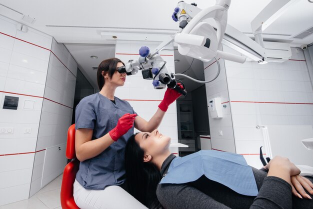 The dentist looks through a microscope and performs surgery on the patient