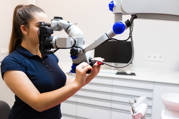 Foto il dentista guarda attraverso il microscopio.