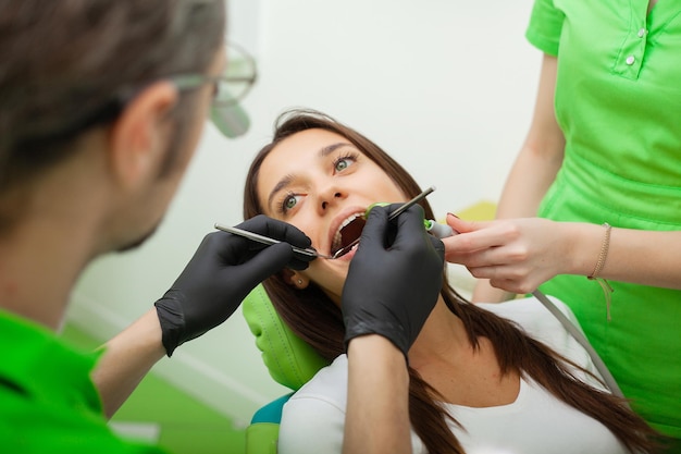 The dentist man are treating teeth to client in dental office