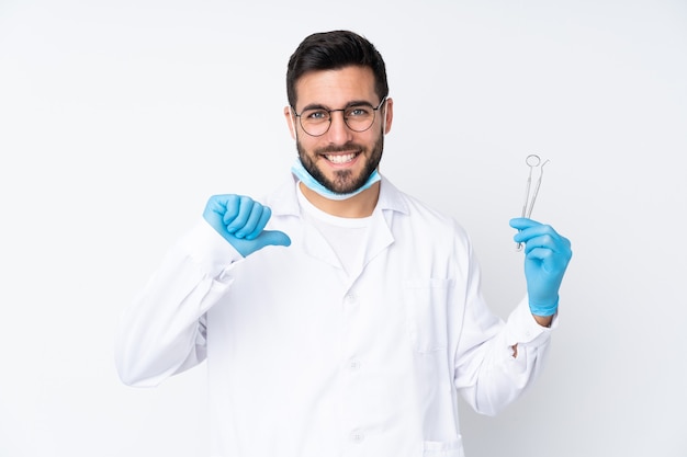 Dentist man holding tools isolated on proud and self-satisfied