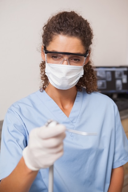 Foto dentista in maschera e occhiali protettivi in ​​possesso di trapano