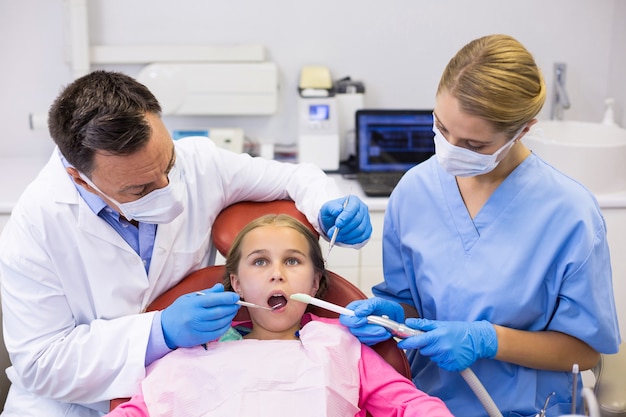 Dentist and nurse examining a young patient with tools