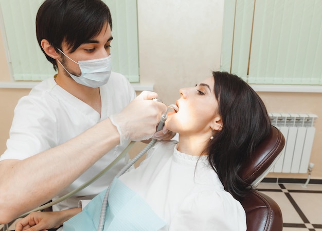 Dentist and patient in the dental office The doctor treats the teeth of a young woman with a drill Hygiene and healthy teeth