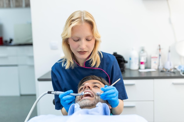 Dentist and patient at medical center Doctor treats a man teeth with dental drill Orthodontist and prosthetics appointment Hygiene and teeth healthy