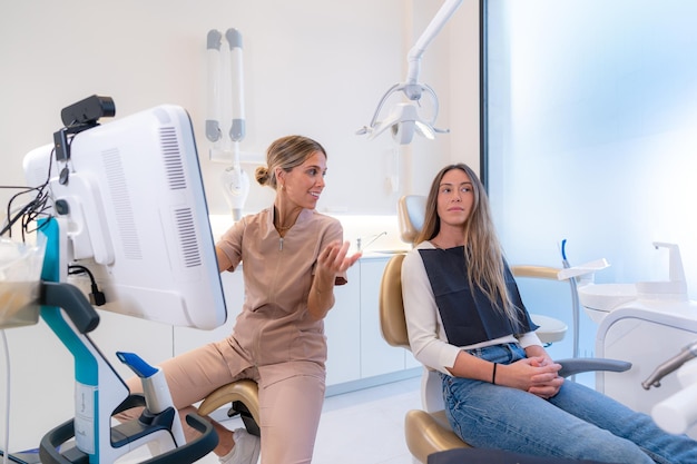 Dentist and patient talking about treatment in a clinic while looking at a screen