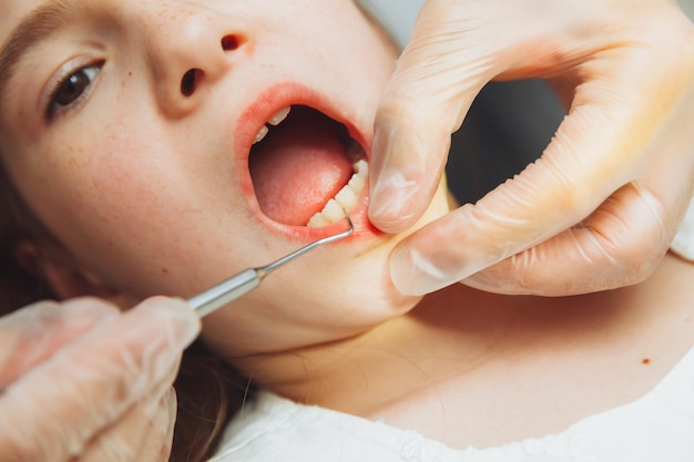 Foto il dentista esegue una procedura di esame su una bambina carina bambina seduta nell'ufficio del dentista