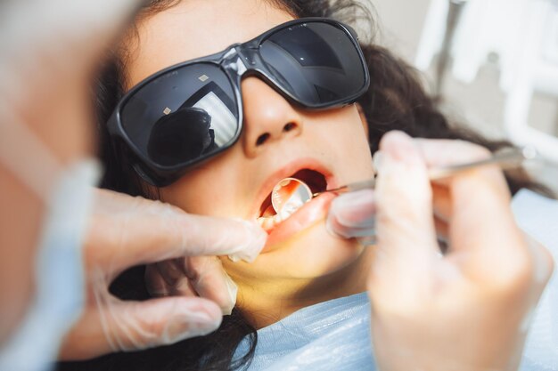 Стоматолог проводит осмотр милой маленькой девочки Маленькая девочка сидит в кабинете дантиста