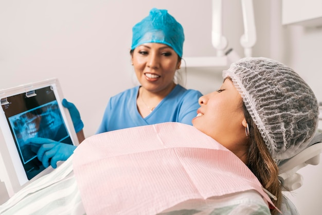 Стоматолог указывает рентгеновский снимок пациенту, лежащему на носилках в стоматологической клинике