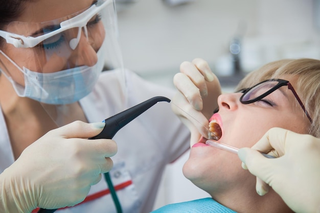 Foto dentista con maschera protettiva che lava la bocca dalla polvere e dal sangue dei denti