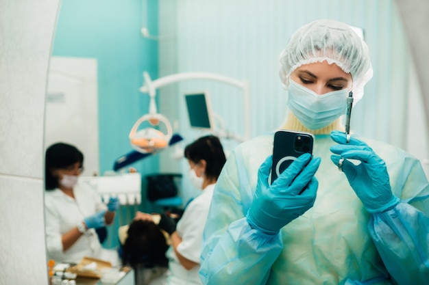 Il dentista con una maschera protettiva si trova accanto al paziente e scatta una foto dopo il lavoro.