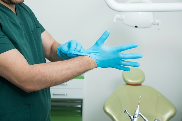 The dentist puts on gloves before work