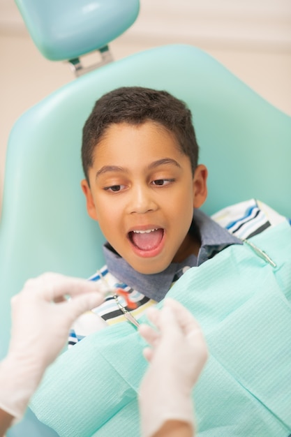 Dentist putting guard. Boy opening mouth while dentist wearing gloves putting mouth guard