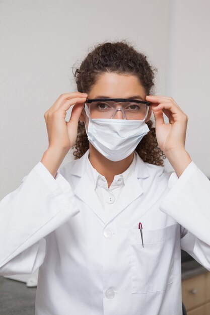 Dentist putting on protective glasses looking at camera