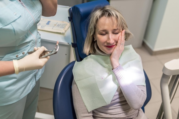 Photo dentist removes the tooth patient at the dental clinic