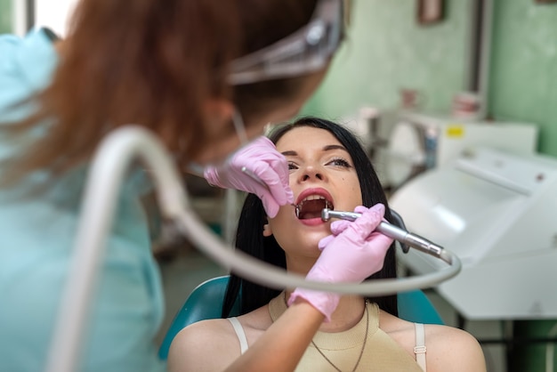 Dentista che esamina i denti del paziente con lo specchio in guanti protettivi