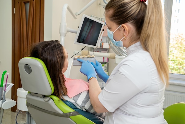 Dentist's hand holding tooth color and examining patient's teeth Bleaching dental care implants for veneers