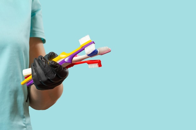 Photo dentist's hand in protective glove with toothbrushes