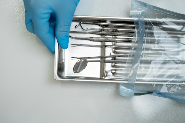 Dentist's hands in blue gloves hold a tray of dental instruments. space for text