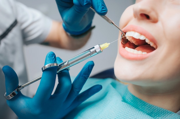 Dentist's hands holding tool and syringe in hands.