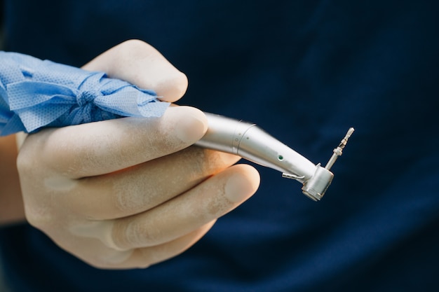 Dentist's hands with gloves working with dental drill in dental office