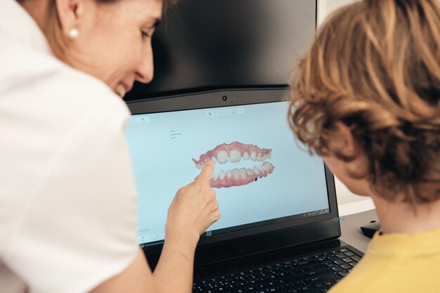 Dentist showing 3d teeth scan to faceless boy